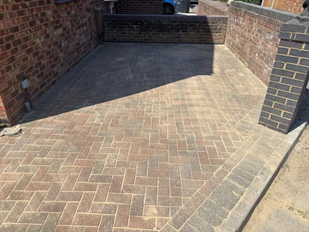 Herringbone block paving driveway between brick walls